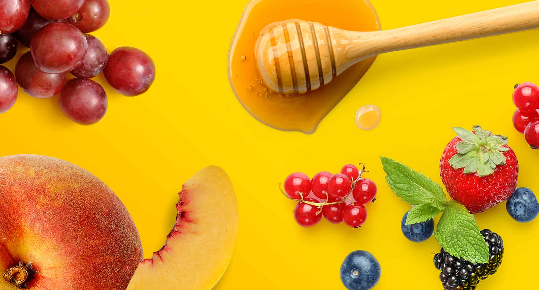 Honey, peach, grapes and mixed berries strewn across a yellow background